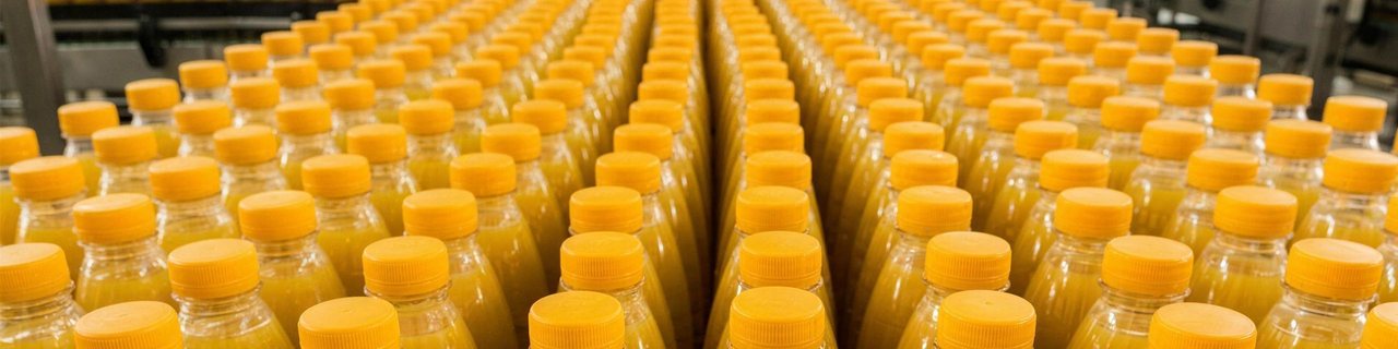 Rows of capped bottles of orange juice on the line, ready for trade distribution